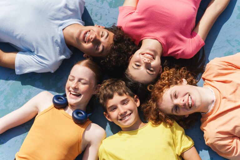 Group of happy teenagers kids outdoors on the sportive field at daytime