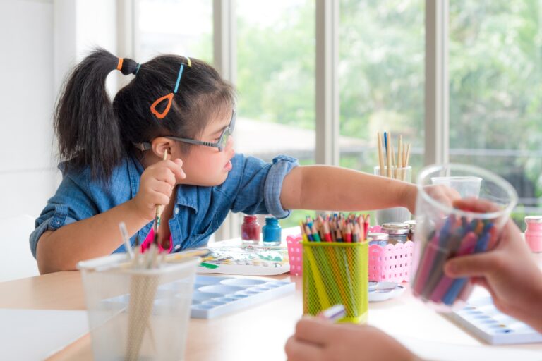 Young autism disabled child complex genetic disorders kid drawing a picture by watercolor.